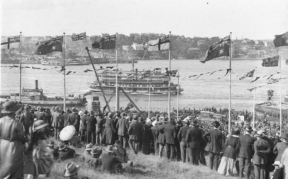 Crowds cheer from flag bedecked Dawes Point. Two ferries and a North Sydney vehicular ferry pass by, photographs by Sam Hood, 1925, Home and Away - 2157
