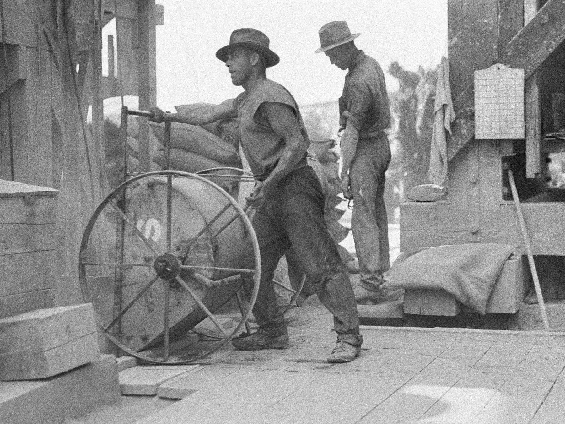 Workmen mixing and pouring concrete with small hand-wheeled hoppers, photograph by Ted Hood, 1930 - 1932, Home and Away – 2262
